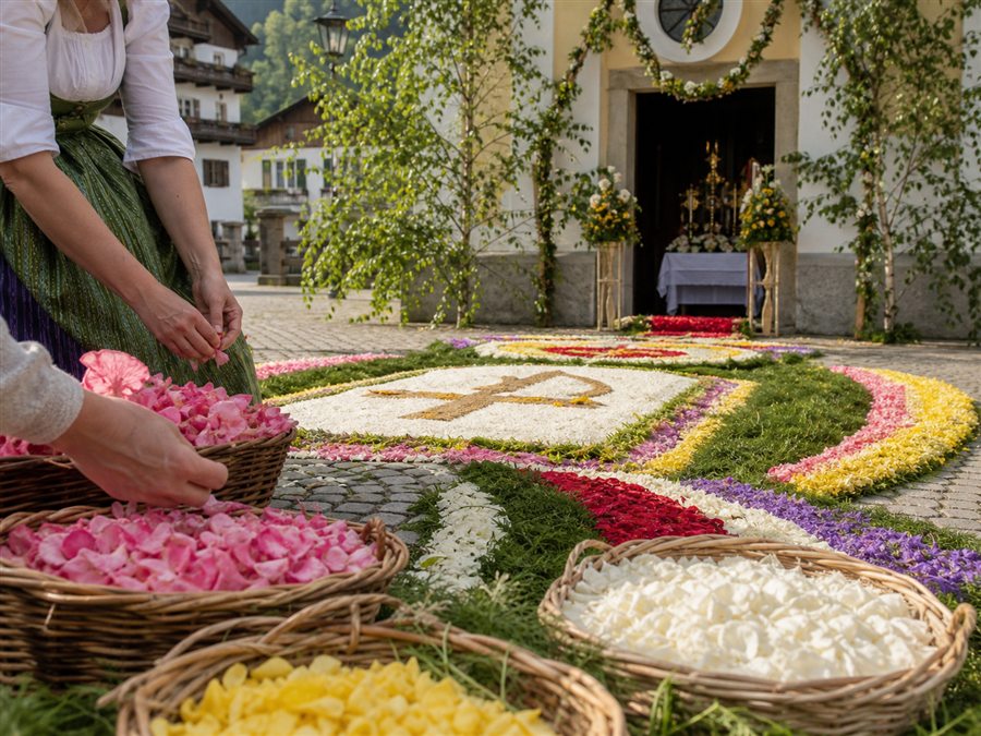 Farbenprächtiger Blumenteppich vor einer österreichischen Kirche als regionaler Fronleichnamsbrauch
